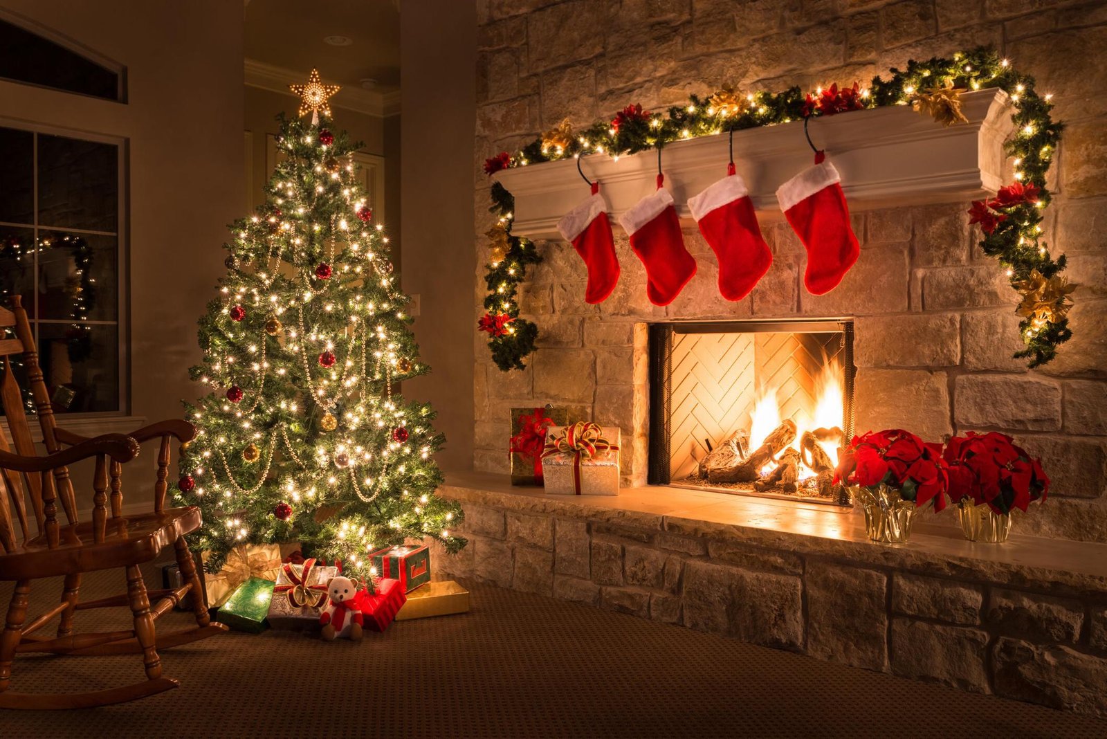 Christmas-decorated living room with a glowing fireplace, stockings, and a tree.