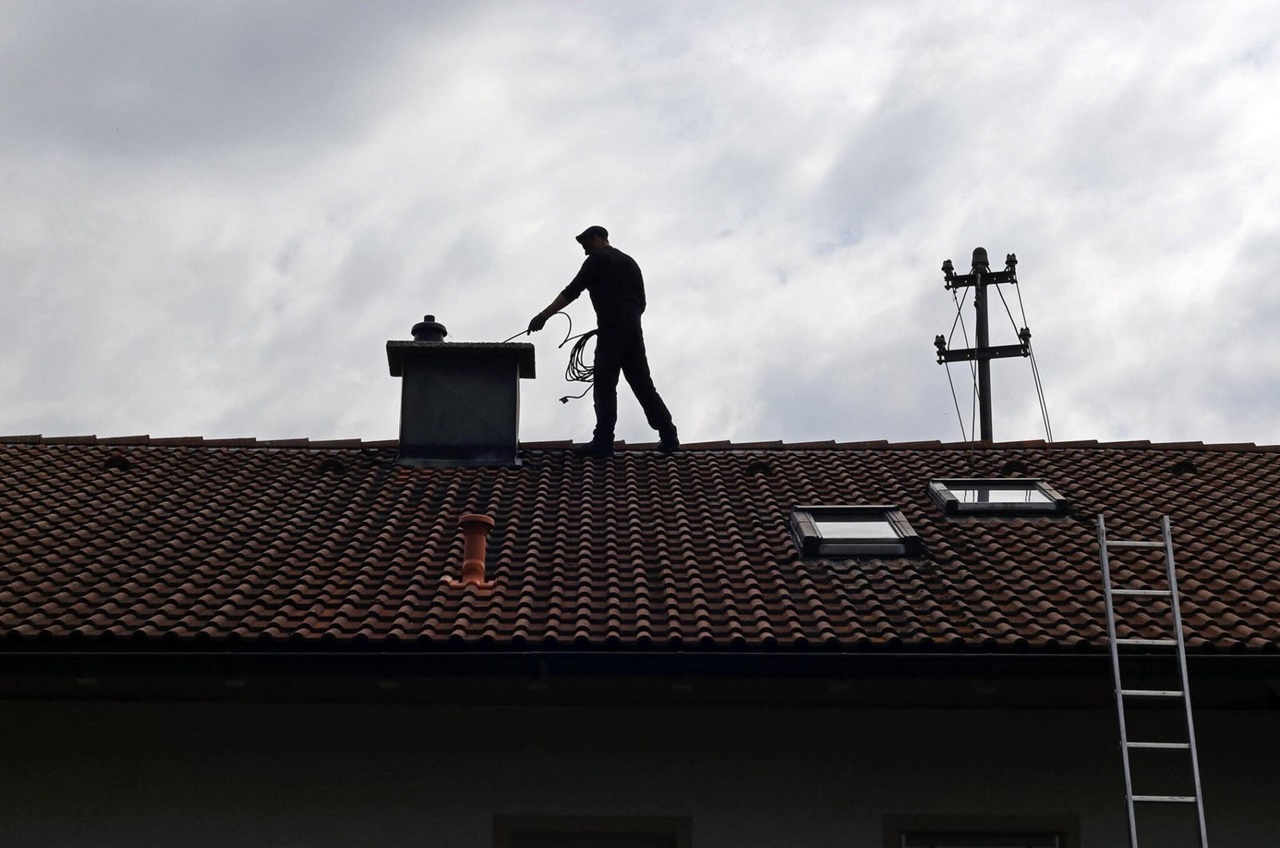 Professional chimney sweep cleaning a house roof chimney
