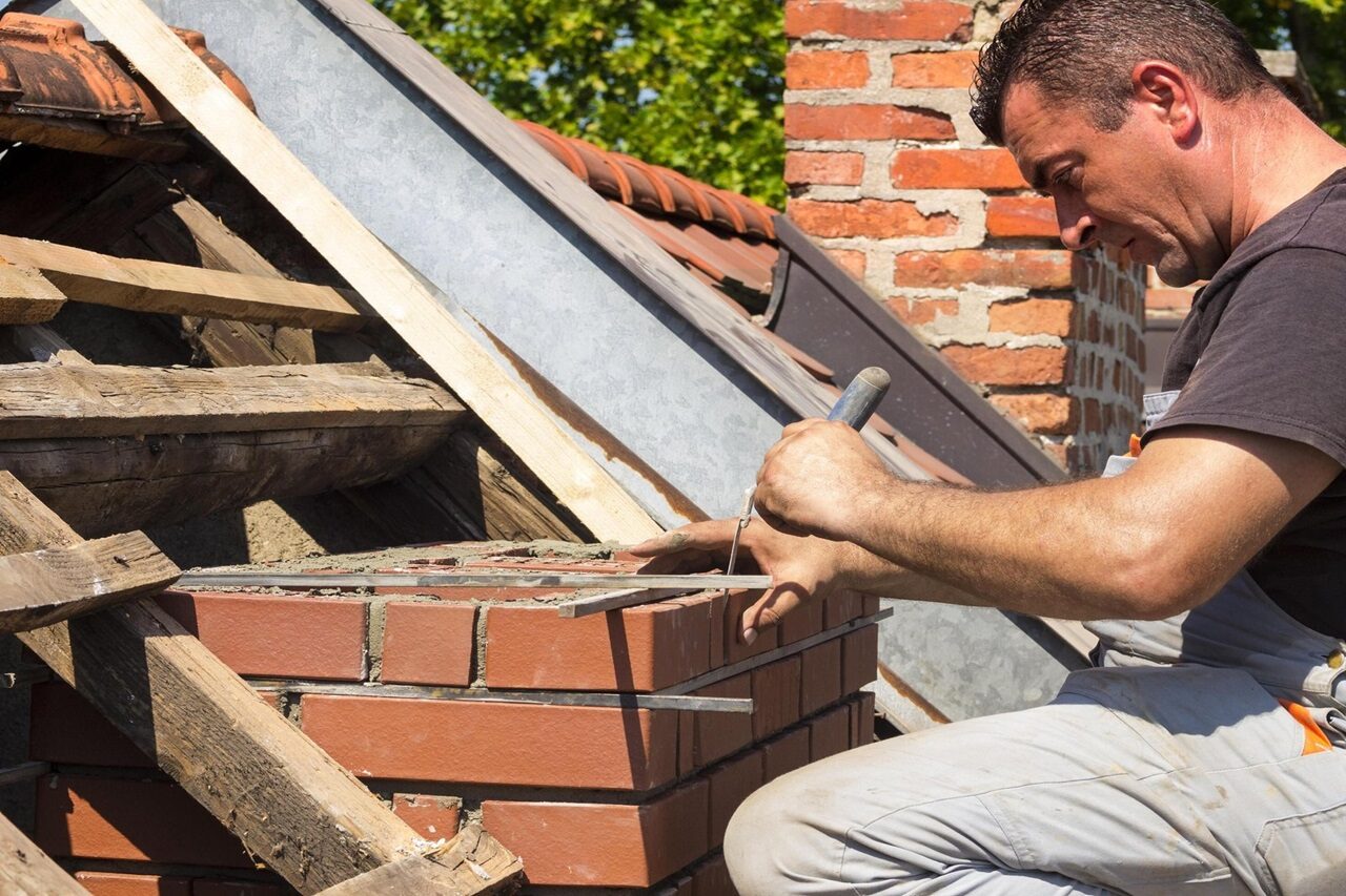 Worker preparing a new brick chimney on a rooftop