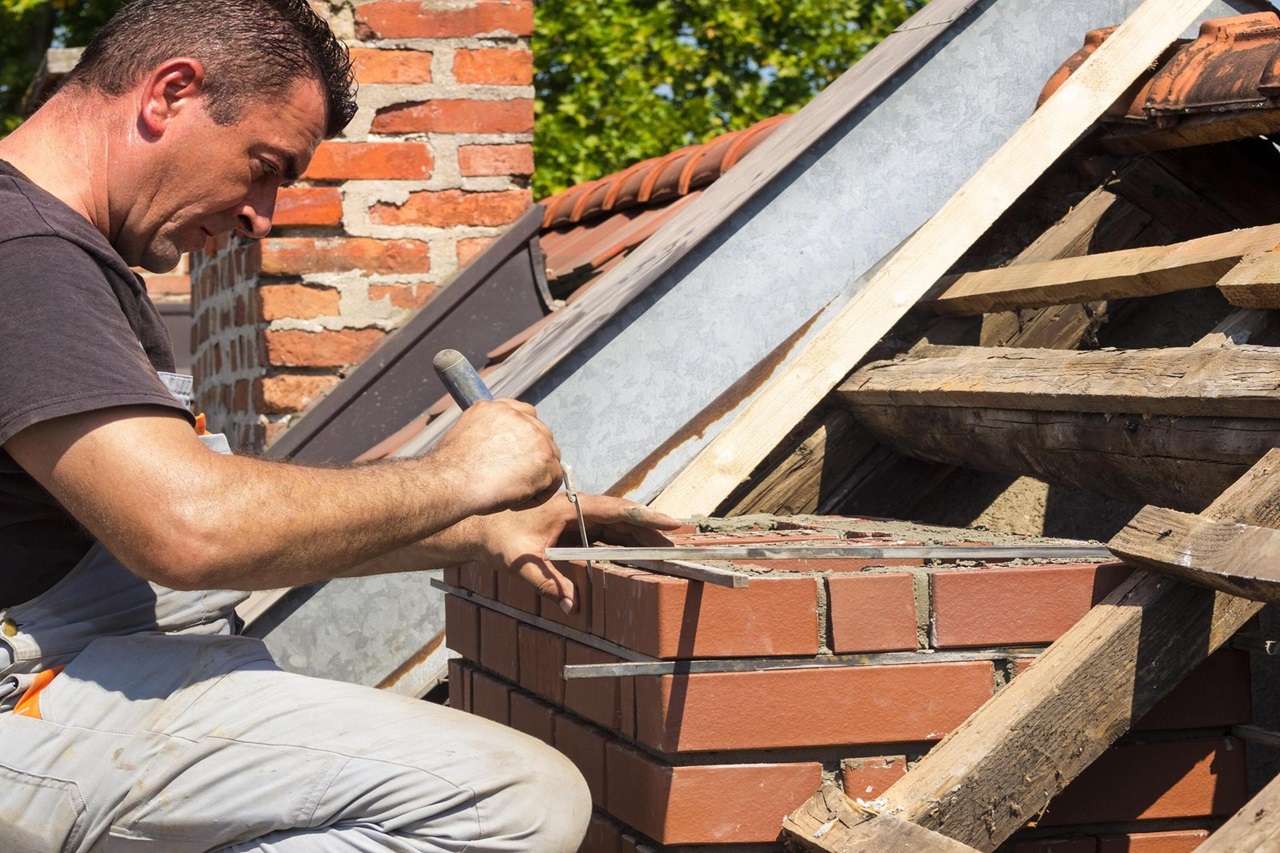 Worker preparing a new brick chimney on a rooftop